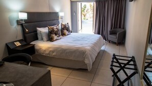 A hotel room with a bed, bedside tables, a chair, a desk, and a view of the outdoors.