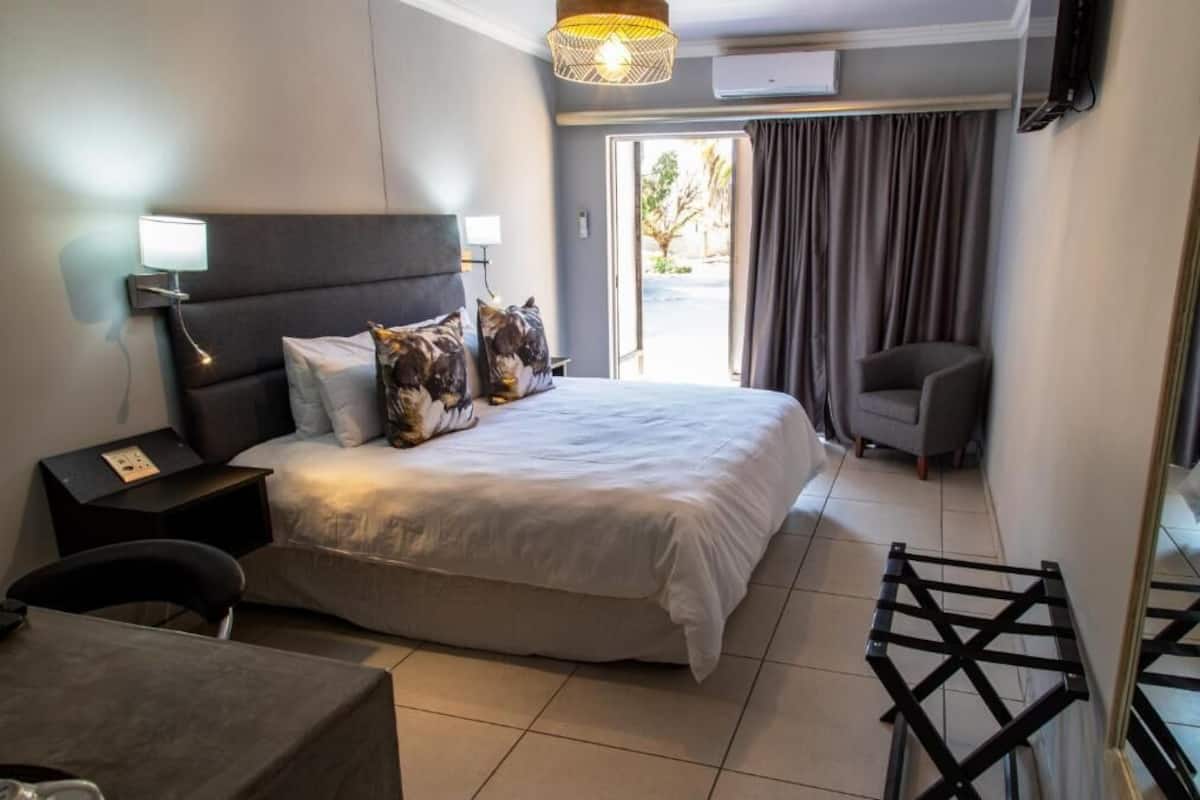A hotel room with a bed, bedside tables, a chair, a desk, and a view of the outdoors.