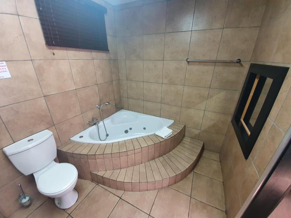 A bathroom with a toilet, a bathtub, and a shower area.