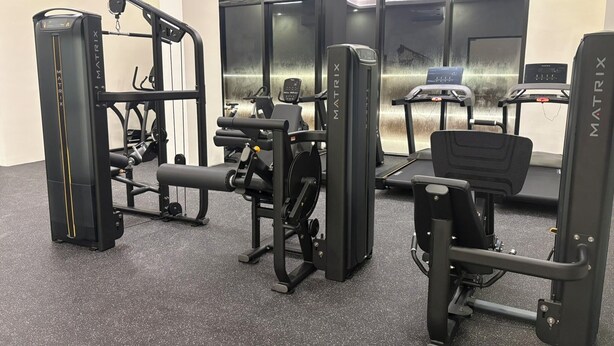 A gym with various exercise equipment, including a squat rack, bench press, and treadmills. - San Francisco Cancun (Cancun)