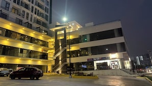 Edifício de vários andares com escadaria central, estacionamento e fachada visível com sinalização.