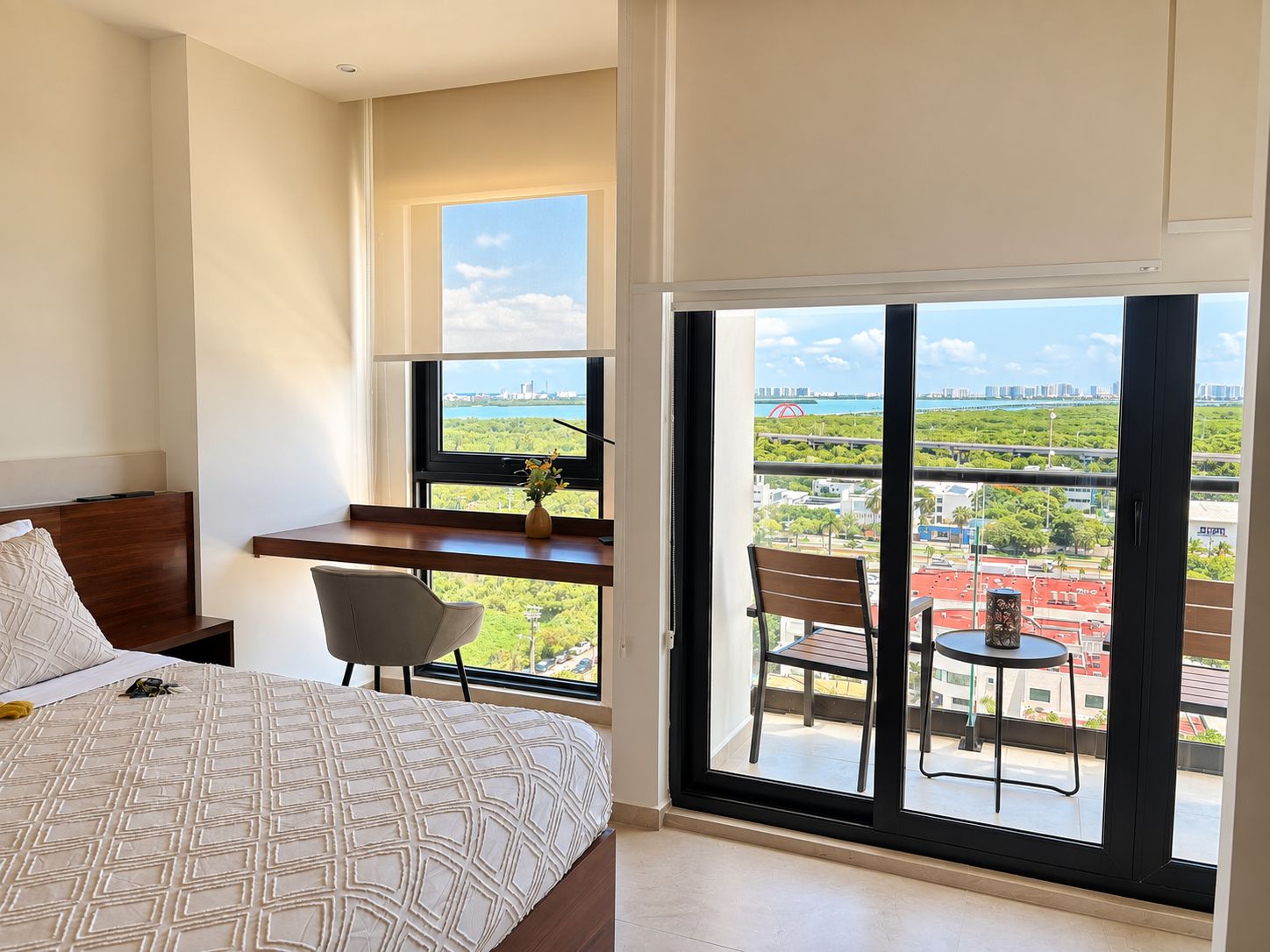 Une chambre à coucher comprenant un lit, un bureau et un balcon avec des chaises et une table.