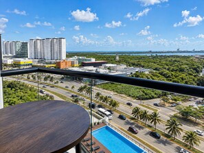 A balcony with a view of a cityscape, including buildings and a road with palm trees. - San Francisco Cancun (Cancun)