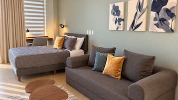 A modern bedroom with a bed, a sofa, a desk, and a lamp.
