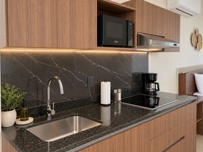 A modern kitchen with a built-in microwave, stainless steel sink, and a coffee maker.