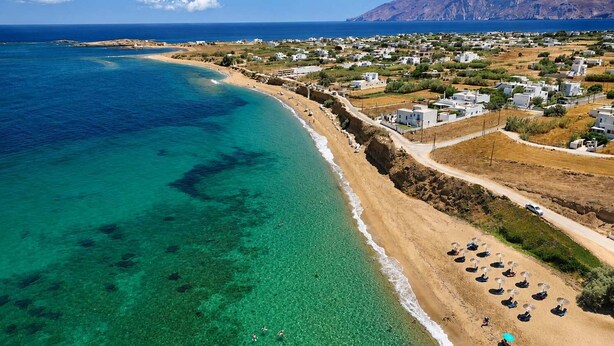 An aerial view of a coastal area with clear turquoise waters, a sandy beach, and a residential area with white buildings. - Hotel Elena - Cozy Seaside Double Suite in Skyros (Skyros)