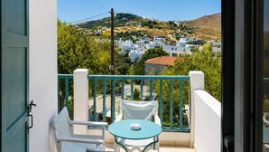 A balcony with a table and chairs, overlooking a hillside with white buildings. - Hotel Elena -Sunny Seaside Balcony Suite in Skyros (Skyros)