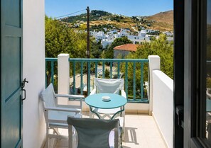 Ein Balkon mit Tisch und Stühlen mit Blick auf eine Hügelslandschaft und weiße Häuser.