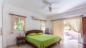 A bedroom with a bed, two bedside tables, a ceiling fan, and a window with curtains. - Alicia Beach, Hispanola Sol! (Sosúa)