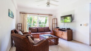 A living room with a sofa, chairs, a coffee table, a TV, and a ceiling fan. - Alicia Beach, Hispanola Sol! (Sosúa)