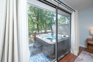 Una habitación con puerta de cristal corredera que da a un balcón con hidromasaje.