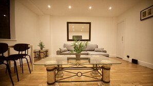 A living room with a glass coffee table, a sofa, and two chairs. - Stylish flat in Oxford Circus (Londra)