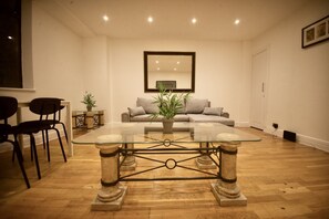 Ein Wohnzimmer mit Glastisch, einer Couch und zwei Sesseln.