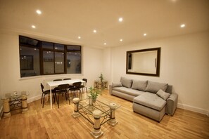 Ein Wohnzimmer mit Esstisch, Sofa und einem Glastisch mit Pflanze.