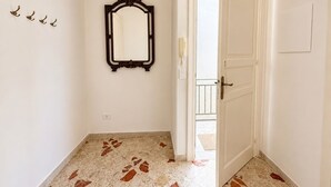 Ein Korridor mit Marmorboden, einer Tür und einem an der Wand befestigten Spiegel.