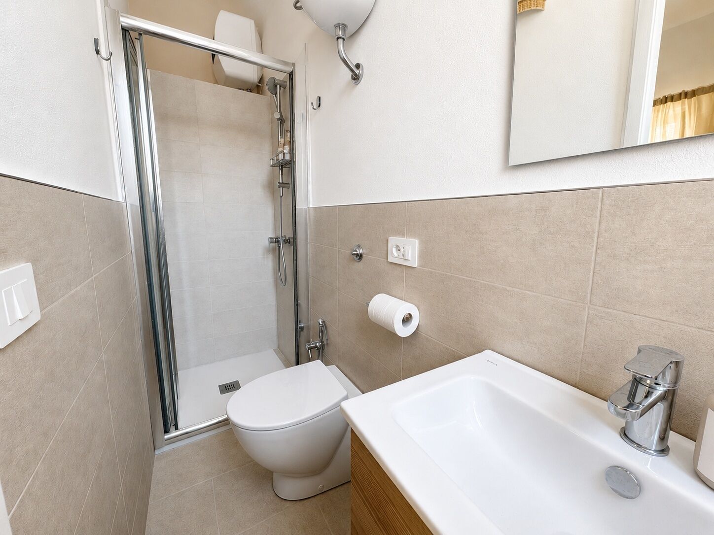 Un bagno con doccia, WC, lavandino e specchio.