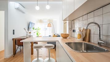 A modern kitchen with a central island, bar stools, a sink, and a dining area with a table and chairs.