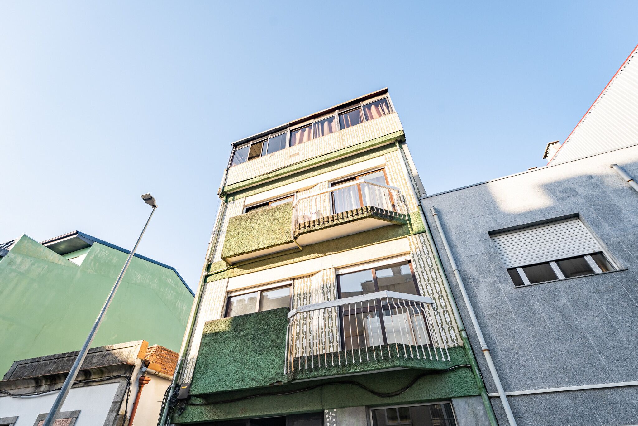 A multi-story building with balconies, a flat roof, and a clear sky.
