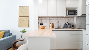 Una cucina moderna con mobili bianchi, un piano di lavoro in legno, un forno a microonde e un lavello.