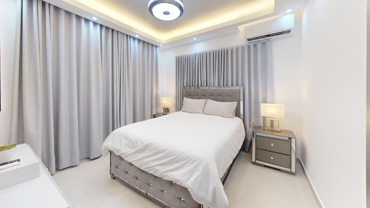 Ein modernes Schlafzimmer mit einem großen Bett, Nachttischen und einer Deckenleuchte.