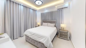 A modern bedroom with a large bed, bedside tables, and a ceiling light fixture. - Exclusivo zona A (Santiago de los Caballeros)