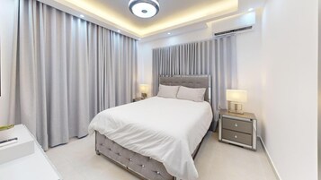 Um quarto moderno com uma cama grande, mesas de cabeceira e um lustre.