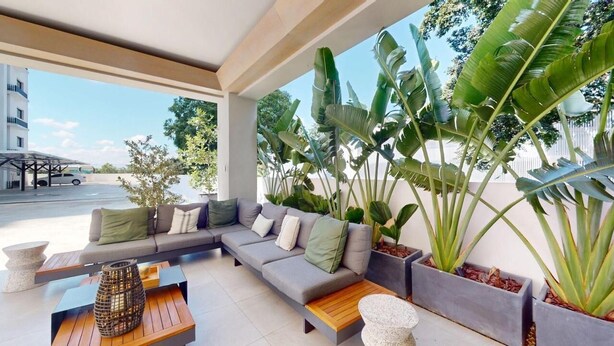 A covered outdoor seating area with a sofa, coffee table, and planters. - Exclusivo zona A (Santiago de los Caballeros)