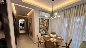A dining area with a round table, chairs, a potted plant, and a painting on the wall. - Exclusivo zona A (Santiago de los Caballeros)