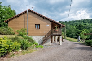 A wooden building with a stone foundation, a covered porch, and a gravel driveway.