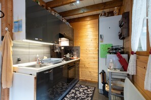 Une cuisine équipée d’un lave-vaisselle, d’une cuisinière, d’un évier et dont les murs sont en bois.