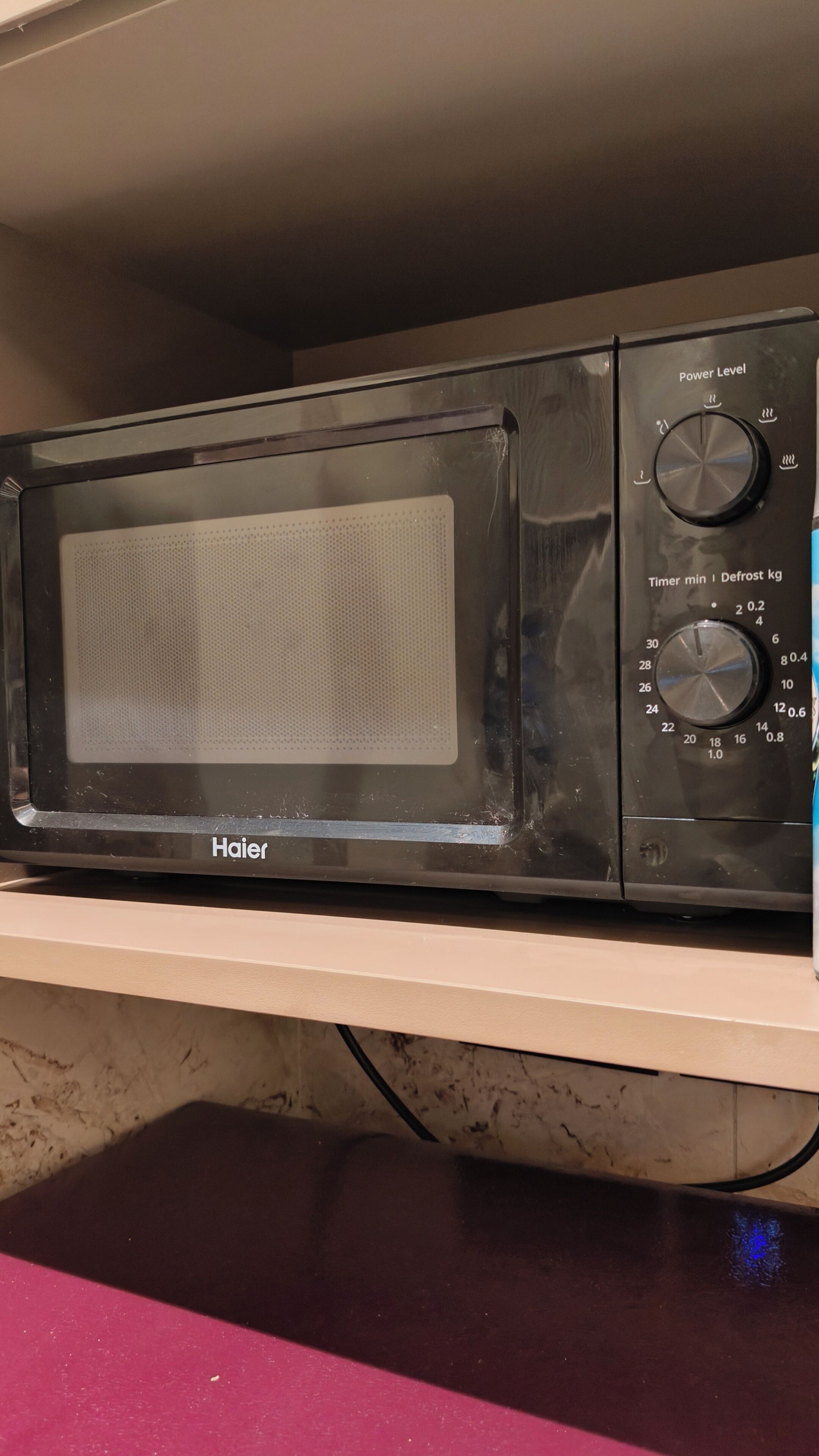 A Haier microwave oven with a digital display, timer, and defrost settings.