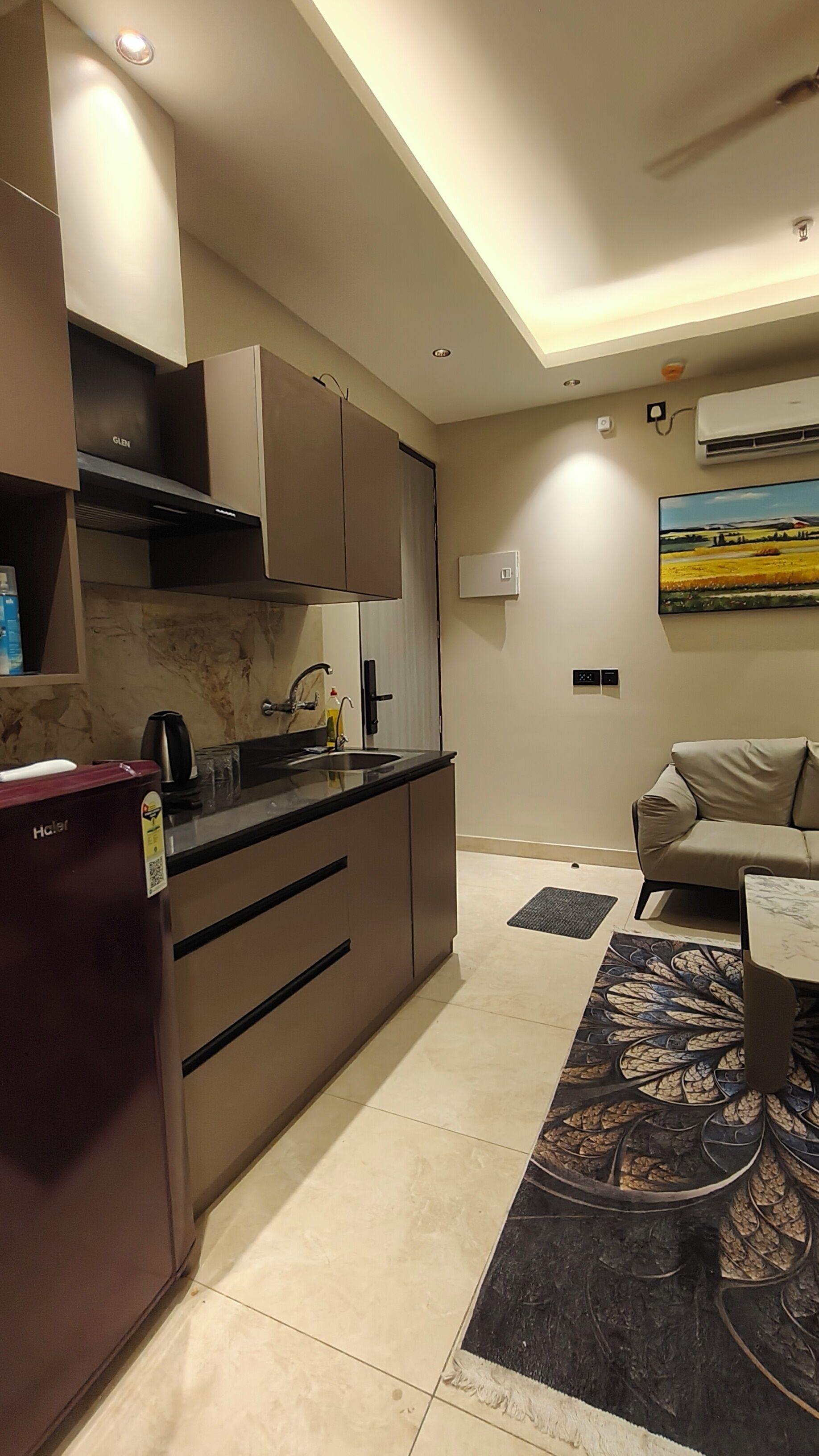 A modern kitchen with a refrigerator, stove, and sink. There is a dining area with a table and chairs.