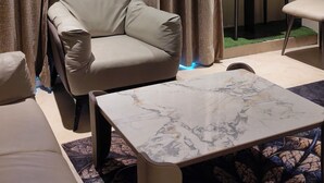 A modern living room with a sofa, a coffee table, and a dining area with a table and chairs.