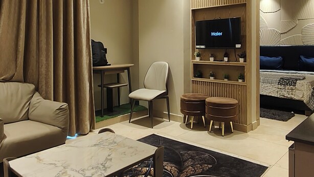 A modern hotel room with a sofa, a coffee table, a TV, a desk, and a bed.