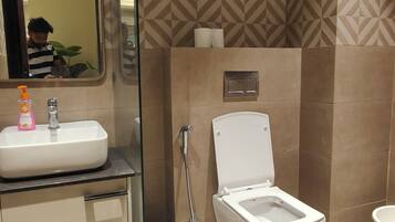 A bathroom with a sink, mirror, toilet, and shower.