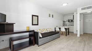 Ein modernes Wohnzimmer mit einer Couch, einem Fernseher, einem Essbereich und einer Küche.