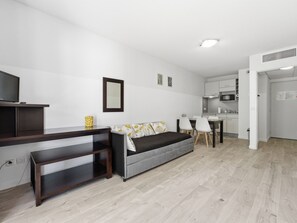 Ein modernes Wohnzimmer mit einer Couch, einem Fernseher, einem Essbereich und einer Küche.