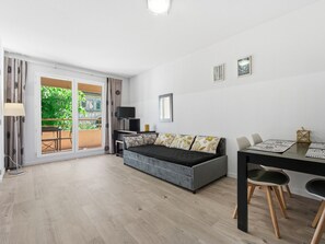 Ein modernes Zimmer mit einer Couch, einem Esstisch und einem Fernseher.