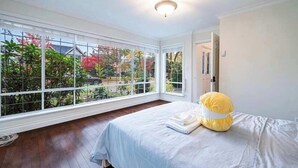 A bedroom with a large window, a bed, and a yellow pillow. - Comfortable Room in a Shared Home (Vancouver)