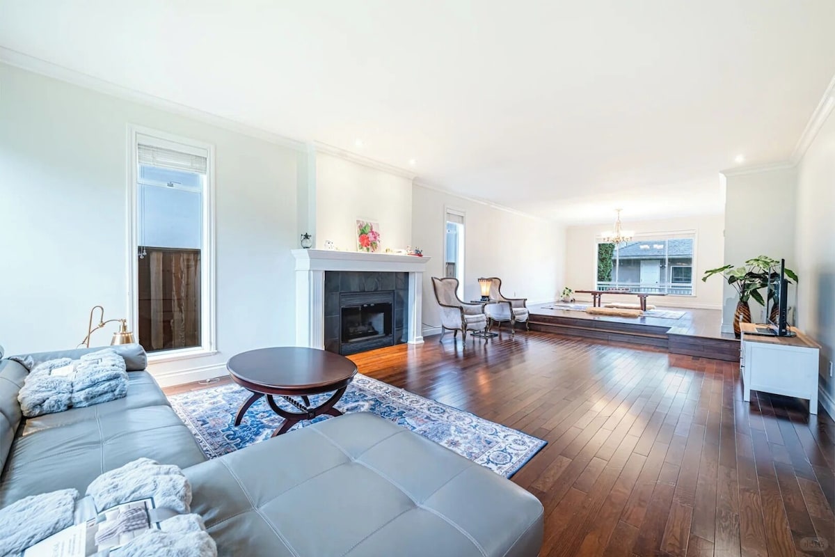 A spacious living room with a fireplace, a sofa, a coffee table, and a dining area with chairs.