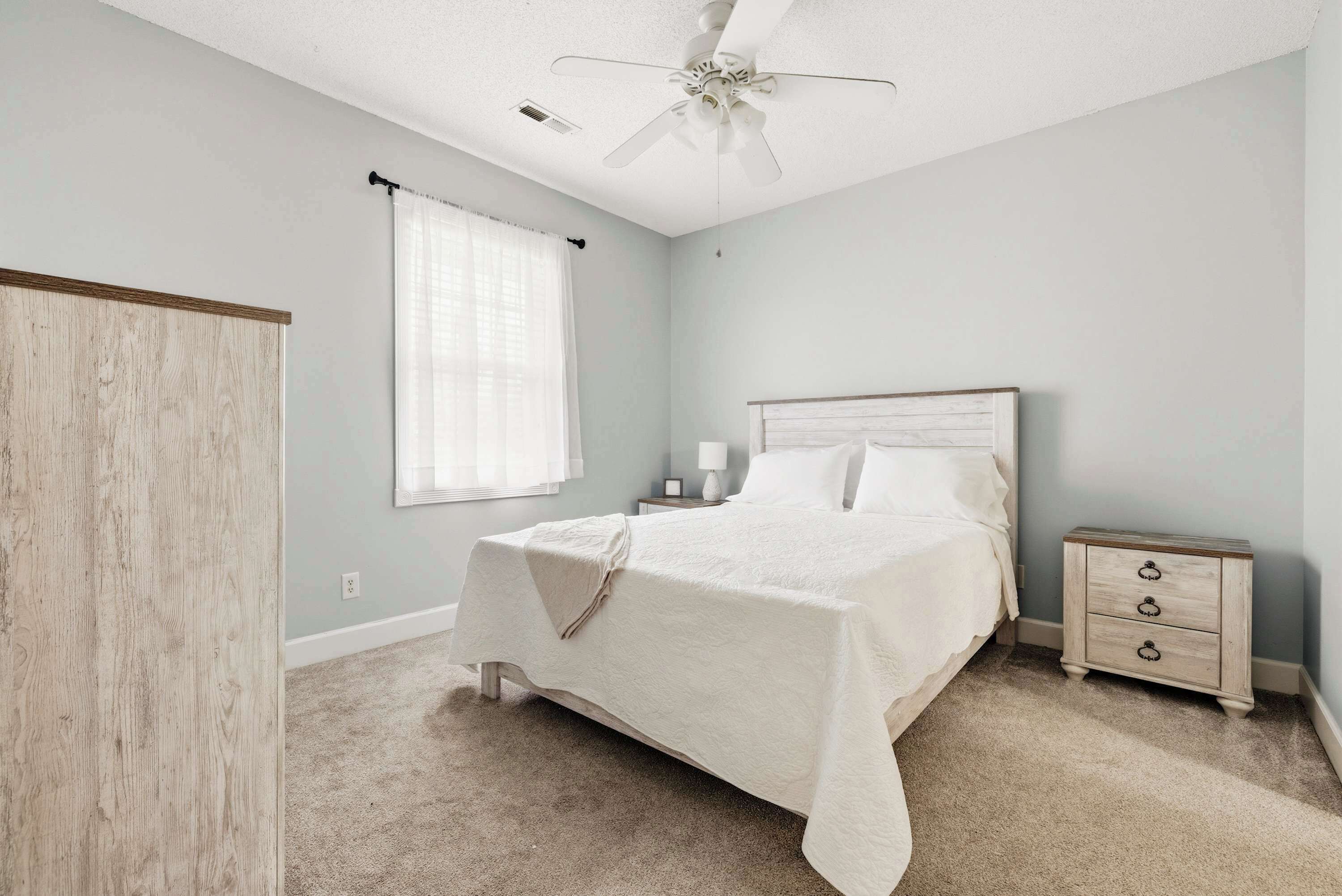 A bedroom with a bed, nightstand, and a ceiling fan.