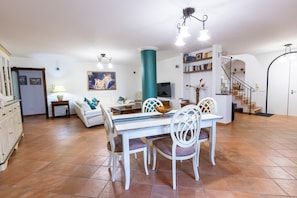 A spacious living room with a dining area, a staircase, and a TV.