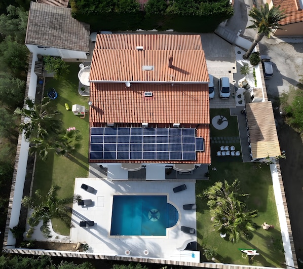 A residential property with a swimming pool, solar panels, and a tiled roof.