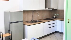 A compact kitchen with a stainless steel refrigerator, a sink with a faucet, and white cabinets. - RP03 - Cesenatico, new apartment near the sea (Cesenatico)