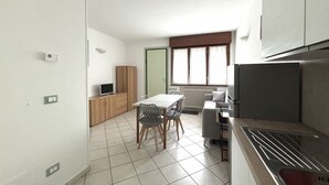 A compact kitchen with a dining area, a built-in oven, and a window with curtains. - RP03 - Cesenatico, new apartment near the sea (Cesenatico)