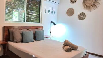Une chambre à coucher avec un lit, des oreillers, une table de chevet, une lampe et des éléments décoratifs sur les murs.