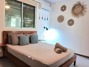 Ein Schlafzimmer mit Bett, Kissen, Nachttisch, Lampe und Wanddekorationen.