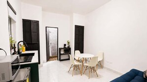 Un espace de vie compact comprenant une kitchenette, un coin repas et un espace détente.