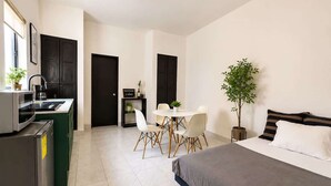 Une chambre d’hôtel compacte comprenant un coin cuisine, un espace repas et un lit.