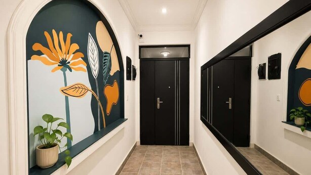 Un couloir avec une porte noire, une plante en pot et un mur orné d’une fresque florale.